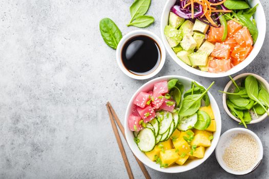 Two assorted poke bowls with raw fish and vegetables, space for text. Top view, close up. Hawaiian dish, rustic stone background. Healthy clean eating concept. Poke with raw fish slices, copy space