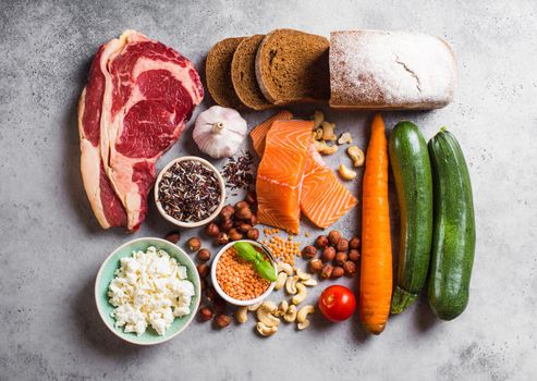 Assortment of healthy balanced food composition: meat, fish, vegetables, bread, cereals, beans, stone background. Raw ingredients for cooking healthy meal, good for diet, clean eating concept