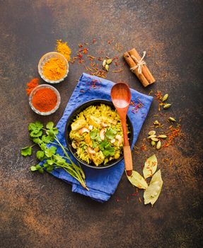 Biryani rice, traditional Indian dish. Biryani spicy rice, chicken, nuts. Indian rice bowl, spices, herbs, rustic stone background. Top view. Space for text. Asian style biryani rice. Indian dinner