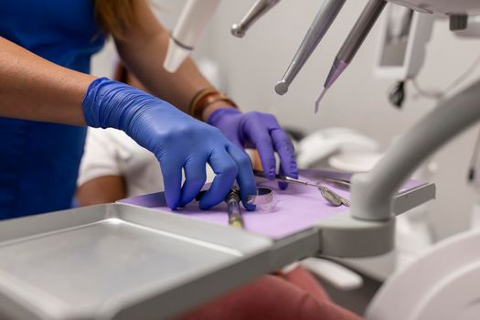 Close up of a female dentist's hands grabbing some tools for the treatment for her patient at the dental clinic