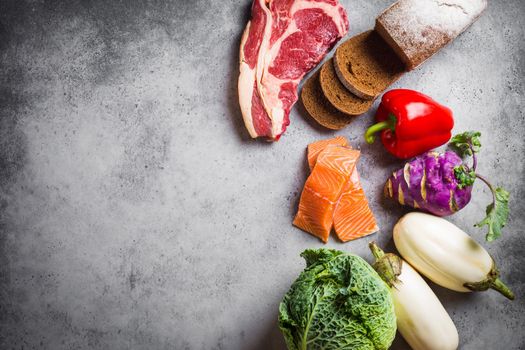 Top view of assortment of healthy balanced food: meat, fish, vegetables, bread, cereals, beans, stone background, space for text. Raw ingredients for cooking healthy meal, good for diet, clean eating