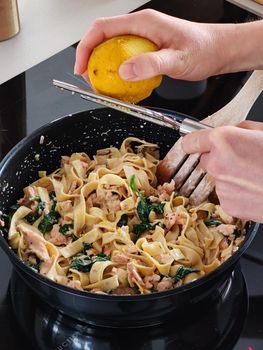 Woman squeeze a lemon on tasty home made seafood pasta in home kitchen, Closeup shot.