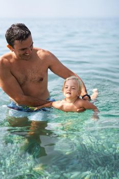 Smiling dad teaching little daughter to swim. High quality photo