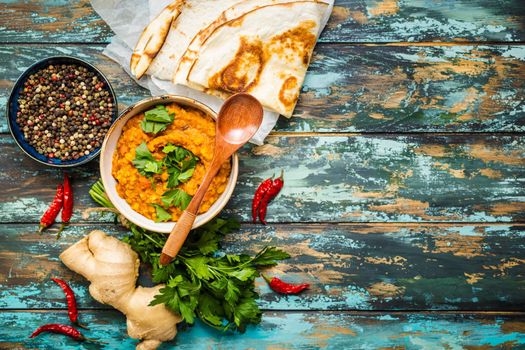 Traditional Indian lentils Dal, naan butter bread. Space for text. Indian Dhal spicy curry in bowl, spices, herbs, rustic wooden background. Top view. Indian food. Authentic Indian dish. Copy space
