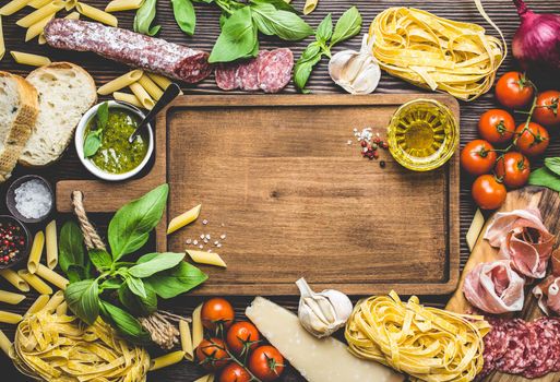 Top view of Italian traditional food, appetizers and snacks as salami, prosciutto, cheese, pesto, ciabatta, olive oil, pasta on rustic wooden board with space for text and retro style