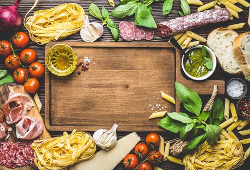 Top view of Italian traditional food, appetizers and snacks as salami, prosciutto, cheese, pesto, ciabatta, olive oil, pasta on rustic wooden board with space for text and retro style