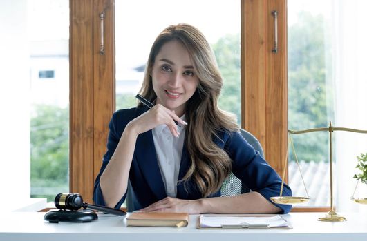 Portrait, Attractive and charming young Asian businesswoman or female executive manager sits at her office desk in modern bright office room..