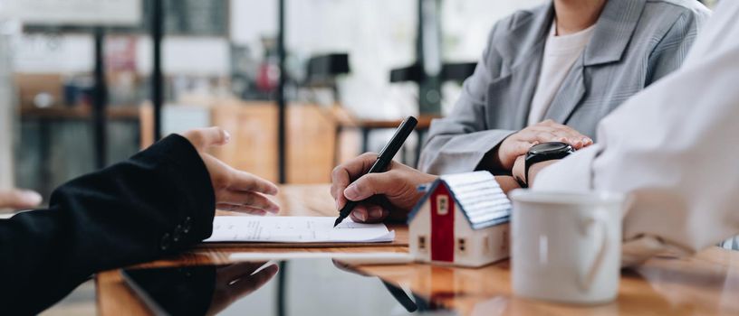 Business woman and young couple signing agreement for buying house. Bank manager and real estate concept