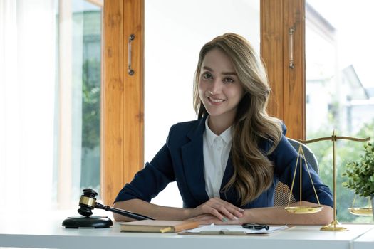 Portrait, Attractive and charming young Asian businesswoman or female executive manager sits at her office desk in modern bright office room..