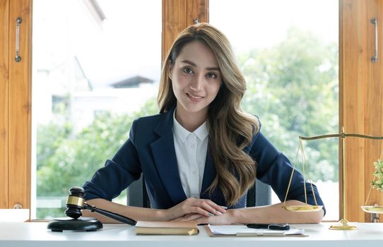 Portrait, Attractive and charming young Asian businesswoman or female executive manager sits at her office desk in modern bright office room..