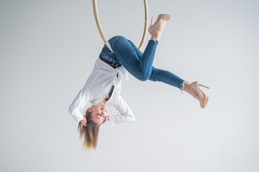 Caucasian woman in casual clothes on an aerial hoop