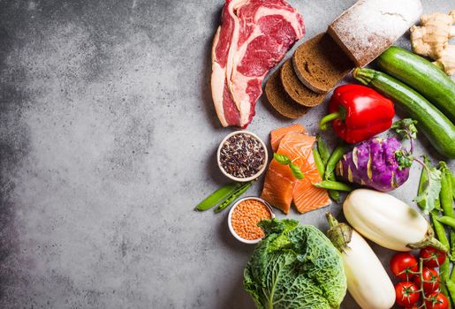 Top view of assortment of healthy balanced food: meat, fish, vegetables, bread, cereals, beans, stone background, space for text. Raw ingredients for cooking healthy meal, good for diet, clean eating