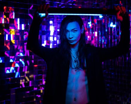 Portrait of a transgender model with a naked torso in a studio with neon lighting