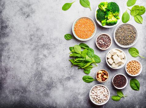 Top view of different vegan protein sources with space for text: beans, lentils, quinoa, tofu, vegetables, nuts, chickpeas, rice, stone background. Healthy balanced vegetarian nutrition for vegans