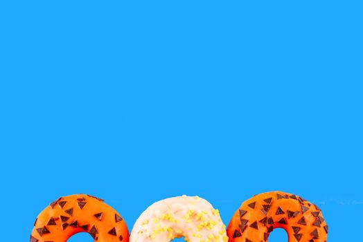 two orange donuts and one white on an blue background Space for text high-quality photos for calendar and cards