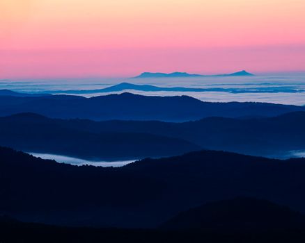 Mountains rise above the clouds in predawn light as seen from the Blue Ridge Parkway in North Carolina.