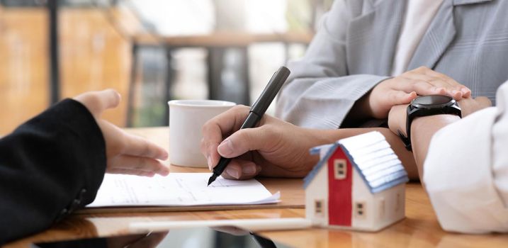 A lovely couple in the meeting with their real estate agent to sign the house contract. Property investment concept. cropped image.