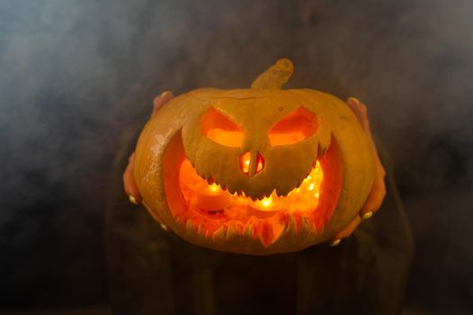 The witch is holding a pumpkin jack about a lantern glowing in the dark. Halloween