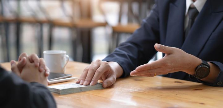 Two businesspeople having a business negotiation meeting in the office, A businessman giving a bribe to his business partner. Cropped and close-up image.