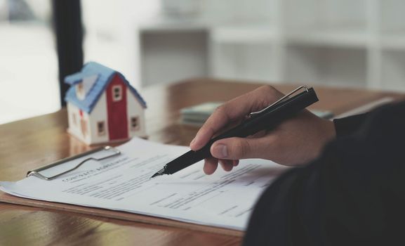 A professional female real estate agent in formal suit at the office desk, checking the rental or property investment contract document. cropped.