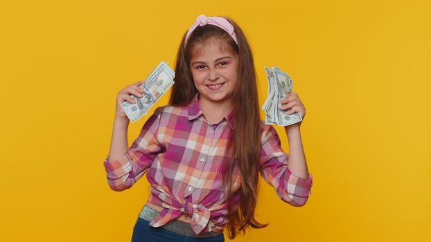 Successful rich preteen child girl kid holding money cash cheering up with high profits, lottery game win, satisfied of wealth income earnings salary dancing listening music. Little toddler children