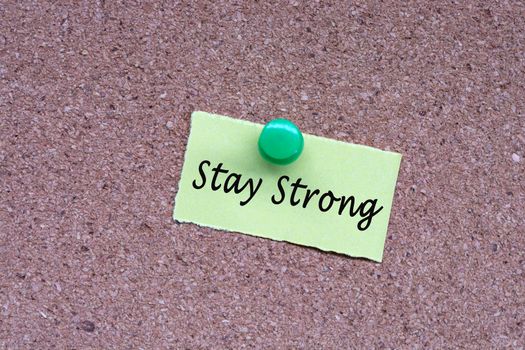 Stay strong words on stick note and pinned to a cork notice board. Business concept.