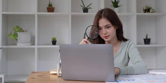 Business analyst using magnifying to review financial graphs, charts. Concept of Analyze return on investment and business analytics growth..