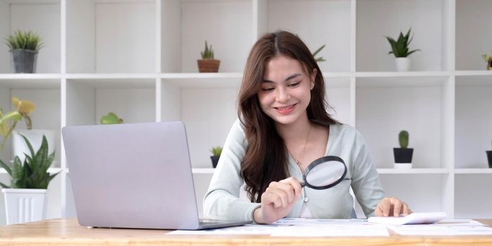 Tax inspector and financial auditor looking through magnifying glass, inspecting company financial papers, documents and reports.