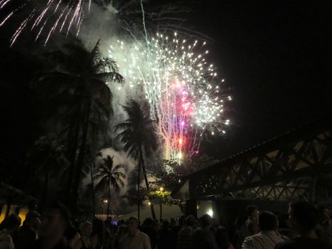 Honolulu - December 31, 2013: New Years Fireworks burst in the air as people watch display at Outdoor New Years Party December 31, 2013 in Honolulu, Hawaii.