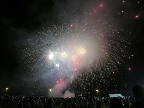 Honolulu - December 31, 2013: New Years Fireworks burst in the air as people watch display at Outdoor New Years Party December 31, 2013 in Honolulu, Hawaii.