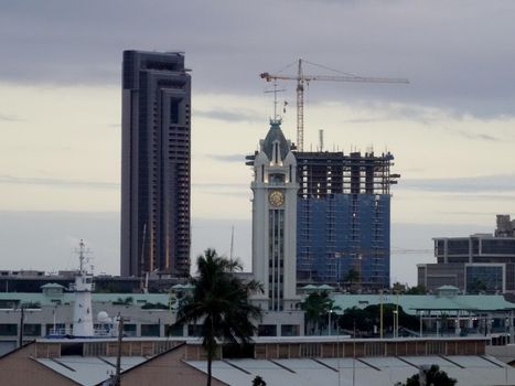 Historic Aloha Tower, which greeting arriving visitors for a century to Honolulu, and skyscraper condos with one under construction in Hawaii.