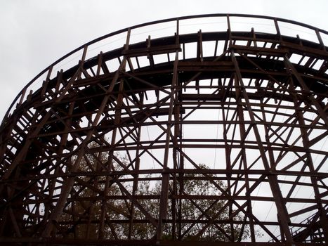 Looking upward at Wooden Rollercoaster against dark cloudy sky.