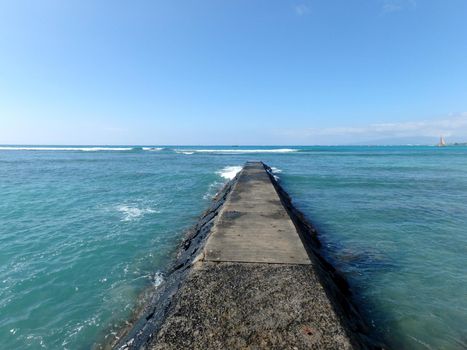 Empty Pier Path into the water in Waikiki with waves in the distance.