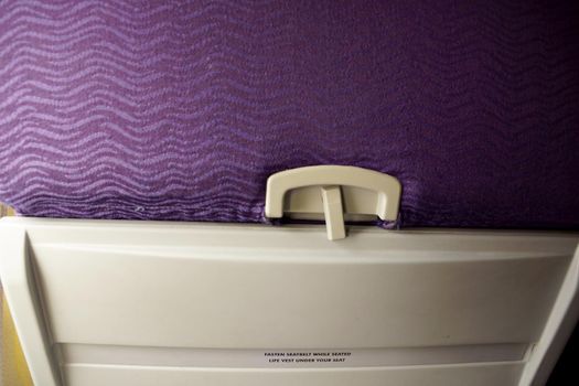 Close-up of Back of Airplane Seat with Purple Clothe and tray table.