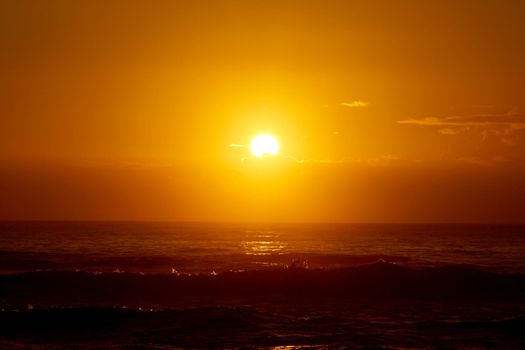 Spectacular Sunrise over the ocean with waves crashing along shore in Hana on Maui, Hawaii.       