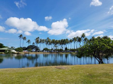 Pond in Ala Moana Beach Park surrounded by trees on a nice day with clouds in the sky on Oahu, Hawaii.  