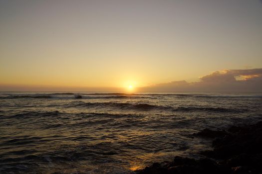 Spectacular Sunrise over the ocean with waves crashing along shore in Hana on Maui, Hawaii.       