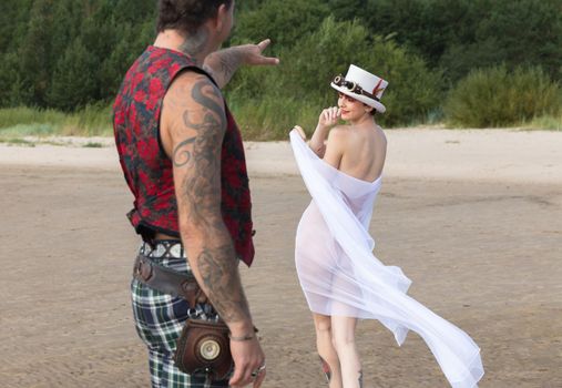 AINAZI, LATVIA – Jul 29, 2019: Love story. Non-traditional wedding photo shoot on the shores of the Baltic Sea. Nude bride in a veil and a spectacular groom