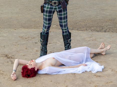 AINAZI, LATVIA – Jul 29, 2019: Love story. Non-traditional wedding photo shoot on the shores of the Baltic Sea. Nude bride in a veil and a spectacular groom