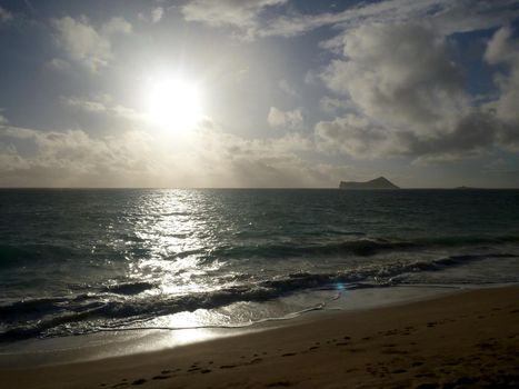 Early Morning Sunrise on Waimanalo Beach on Oahu, Hawaii by Rabbit and Rock Island bursting through the clouds. 2012.