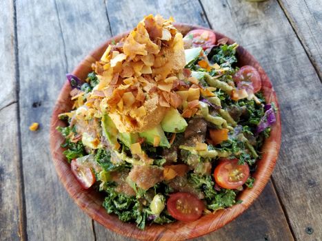 Rainbow Bowl: Kale salad with red cabbage, green onion, carrot, Japanese  cucumbers tossed in ginger tahini dressing.  Served on brown rice.  Topped with avocado, grape tomato, veggie mix, almonds and hummus. 