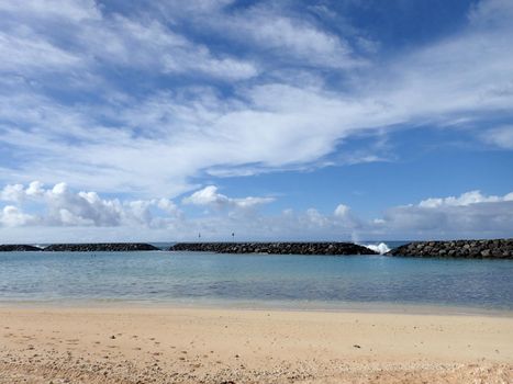 Beach on Magic Island in Ala Moana Beach Park with wave breaking over rocks on the island of Oahu, Hawaii.  On a beautiful day.