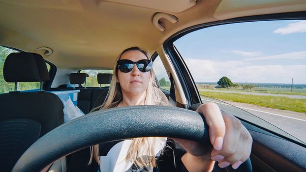 A young woman in a good mood behind the wheel of a car