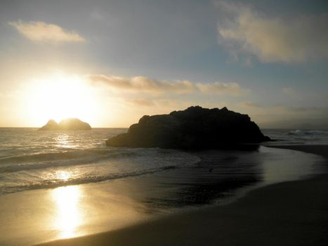 Sunsets over Seal Rock with waves rolling onto beach in San Francisco, California. 