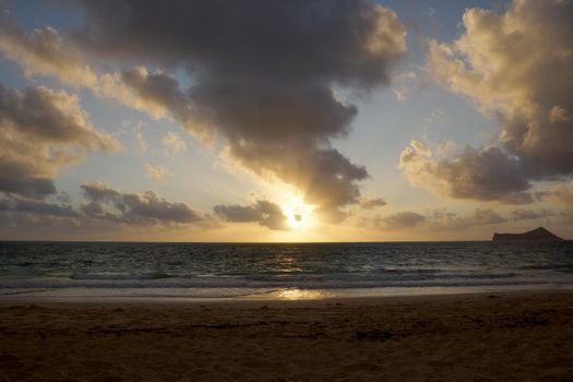 Early Morning Sunrise bursting through the clouds on Waimanalo Beach on Oahu, Hawaii by Manana Island.