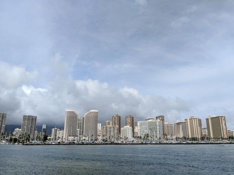 Skyline of Waikiki during day with yachts and boats in Ala Moana harbor, Hotels, Crane, and Hilton Hawaiian in Waikiki, Oahu, Hawaii.  2018