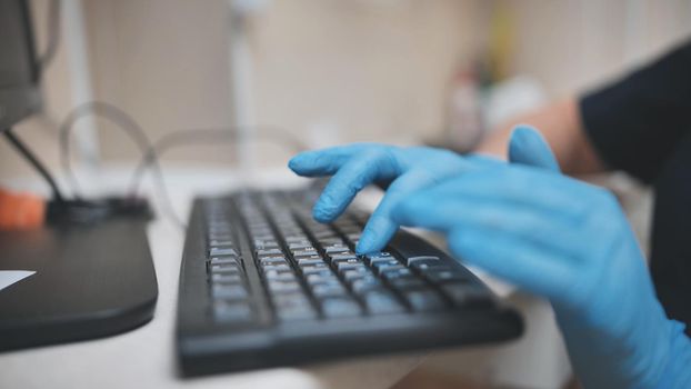 The veterinarian is typing on the keyboard in blue gloves
