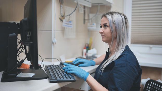 The veterinarian at work is typing on the keyboard at the computer