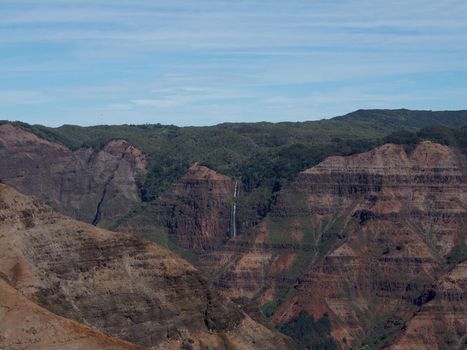 Waterfall flows out of Lush Mountains of Waimea Canyon on Kauai, Hawaii