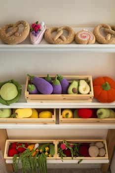 Artificial food in the children's kitchen. On the shelf are vegetables and fruits made of knitted threads.
